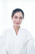 © ultramansk - Portrait of a young Asian woman in a white bathrobe posing confidently with soft natural lighting.