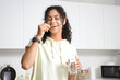 © Pixel-Shot - Young African-American woman taking fish oil in kitchen