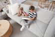 © Pixel-Shot - Cute little boy playing with screwdriver and extension cord on sofa at home. Child in danger