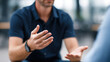 © INT888 - Man blue shirt gesturing with his hands while talking, modern indoor setting, conveying explanation or discussion, with blurred background, natural lighting, casual attire, and watch his wrist
