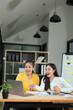 © panomporn - Group of happy Asian business people having a meeting at the office. Two women working together using modern laptops.