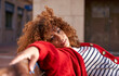 © Westend61 - Curly hair woman staring while lying on bench