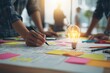 © Petr - Creative UX design team brainstorming ideas with sketches, sticky notes, and light bulb in bright modern workspace