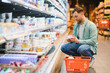 © Serhii - Customer choosing yogurt in dairy products section of supermarket