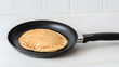 © A2Z AI  - Golden brown pancake in a non-stick skillet on a white countertop, ready to be served. Delicious breakfast food and comforting morning treat.