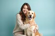 © Vadym - Young smiling woman hugs golden retriever dog, both look at camera. Happy female owner with best friend. Pet care, love, friendship, cuddling on light blue background. Best companion, family pet.