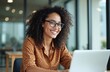 © Vadym - Young hispanic woman smiling using laptop in modern office. Attractive female with curly hair wears glasses working on computer. Pro business lady in workplace with happy face.