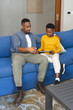 © Wavebreak Media - Father and son sitting on sofa using tablet, enjoying quality time together