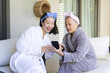 © Wavebreak Media - Smiling Chinese grandmother and granddaughter sharing stories on patio bench, with phone and cup