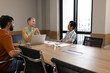 © Wavebreak Media - Sitting Diverse coworkers discussing project at table in meeting room, with laptop and sticky notes