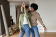 © Wavebreak Media - Smiling diverse couple dancing in new home, with cardboard box and wrapped picture frames