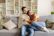 © Home-stock - Sweet loving European couple sitting on couch at home, husband hugging his wife, looking together aside at copy space, cozy living room interior