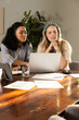 © Wavebreak Media - Working Diverse female coworkers reviewing charts on silver laptop at office with notebook and pen