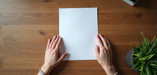 Aufkleber - Top-view shot of hands holding blank white paper sheet on wood desk. Workspace with empty paper for message, letter, text, note, design. Creative writing, office work concept.