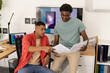 © Wavebreak Media - Reviewing printed documents Diverse male coworkers collaborating in office, with laptop and monitor