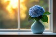 © Color - A blue hydrangea blossom in a vase by the window bathes in the warm glow of sunlight.