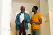 © Wavebreak Media - African American father and son discussing outfits in closet, with burgundy sweater and smartphone
