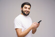 © muse studio - Smiling young man engages with smartphone, capturing modern connection in a minimalist setting