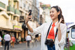 © Chanakon - Young Asian woman traveling backpacker in Khaosan Road outdoor market in Bangkok Thailand. Happy female tourist walking in the downtown street traditional market