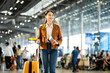 © Chanakon - Portrait of confident young businesswoman smiling at camera ready traveling business trip with holding passport with ticket boarding pass and smartphone at the international airport terminal.