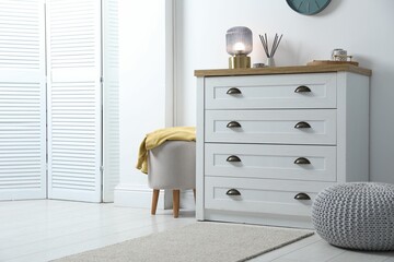 Poster - Dresser with stylish reed diffuser and lamp near white wall indoors