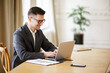© muse studio - Focused professional engages with laptop in a bright office environment, blending productivity and comfort