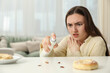 © New Africa - Emotional young woman spraying insecticide onto cockroaches at white table indoors, selective focus. Pest problem