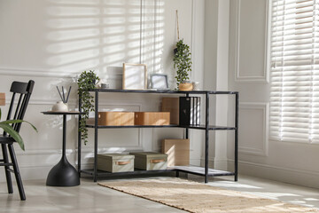 Poster - Console table with different decor and chair near white wall indoors. Interior design