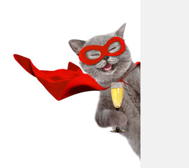 Aufkleber - Happy cat wearing superhero costume looking from behind blank white banner and holds glass of champagne. Isolated on white background