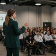 © RickR - Photo of a Woman Presenting to an Audience in a Conference Hall Wearing a Dark Green Suit
