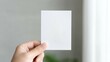 © Kamonwan - A close-up of a hand holding a blank card against a soft, neutral background. This image conveys simplicity, creativity, and the potential for personal expression or communication.