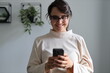 © Andrii Zastrozhnov - Smiling young adult caucasian female using smartphone indoors
