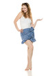 © vladimirfloyd - Young blonde woman in white top and blue skirt, playfully gesturing with raised hand as if holding an imaginary object. Engaging advertising pose