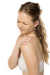 © vladimirfloyd - Young woman in white top grimacing with eyes closed while touching shoulder, demonstrating joint pain or muscle tension against clean white background