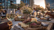 © Maksym - Stylish catering setup on a rooftop with long wooden table, linen napkins, charcuterie boards, and friends reaching for glasses in celebratory mood.