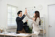 © wichayada - Teamwork and Achievement. Colleagues sharing a joyful moment with high fives in a modern office.