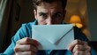 © Татьяна Антоненко - Man is holding a white envelope in his hand, looking at the camera with a serious expression on hi
