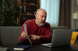 © kinomaster - Elderly Man Checking Documents During Video Call at Home