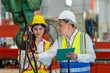 © BESTIMAGE - Factory apprenticeship. Man mentor teaching Female employees trainee operating machine looking monitors and check Production process machinery. foreman explaining woman engineer control machine .