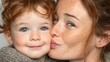 © Anuson - A redhead mother lovingly kisses her adorable toddler child on the cheek in a tender moment of affection.