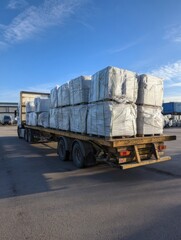 Poster - Concrete Paving Slabs Secured in Film Wrap on Trailer Under a Clear Blue Sky During Daytime Transport