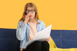 © Pixel-Shot - Emotional young woman reading newspaper on sofa near color wall