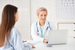 © Pixel-Shot - Happy mature female doctor with laptop and patient working in clinic