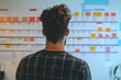 © Meenaxi - Man with curly hair looking at a wall chart with colorful blocks in an office environment space