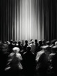 © Milon - A monochrome image showing a crowd of people facing a stage with bright light and vertical curtains