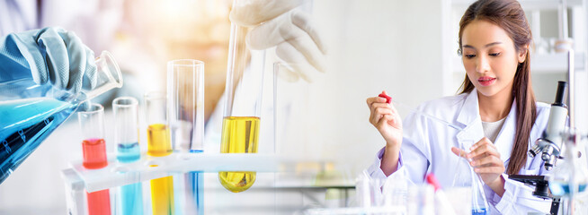 Wall Mural - attractive scientist woman testing chemical sample in flask at laboratory with lab glassware backgro