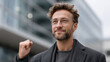 © Denis Yevtekhov - Businessman celebrating with a fist pump outside a modern building, dynamic and victorious, corporate success, urban business, professional triumph, energy.
