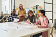 © Mediaphotos - Group of diverse individuals engaged in studying foreign languages in modern classroom environment, reviewing documents and interacting with each other while seated around table