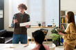 © Mediaphotos - Group of students participating in language learning class, with instructor explaining concept. Natural light illuminating classroom, books and papers on table, creating an active learning atmosphere