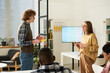 © Mediaphotos - Group of diverse individuals engaged in studying foreign languages in classroom. Two people standing and discussing while others are seated, creating an interactive learning environment